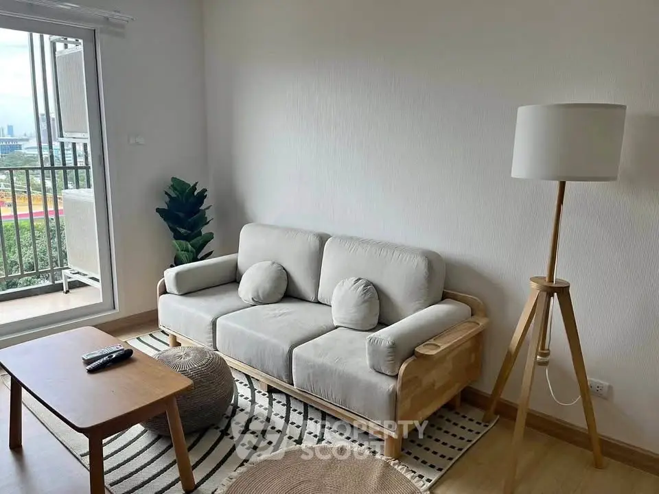 Chic living room with modern sofa, stylish lamp, and balcony view in urban apartment.