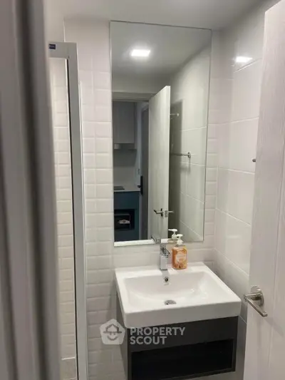 Modern bathroom with sleek sink and large mirror in contemporary apartment.