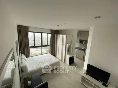 Modern bedroom with city view, featuring sleek furniture and integrated kitchen appliances.