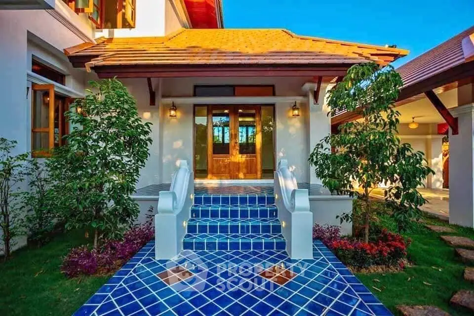 Charming entrance with vibrant blue tiled steps and lush greenery
