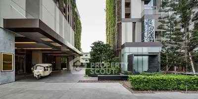 Modern building entrance with lush greenery and sleek architecture.