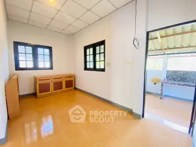 Bright room with tiled floor and outdoor view, featuring wooden cabinet and large windows.