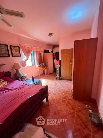 Cozy bedroom with pink walls, wooden furniture, and natural light.