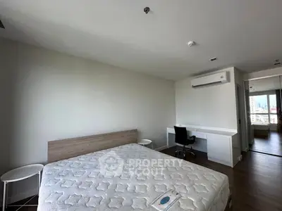 Spacious bedroom with modern furnishings and city view, featuring a comfortable bed and work desk.