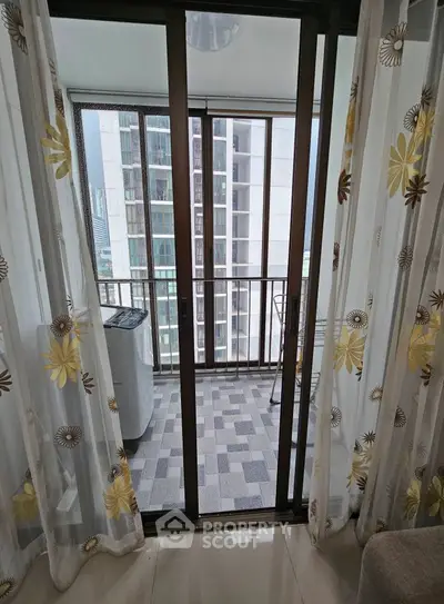 Modern balcony view with sliding glass doors and floral curtains in urban apartment.