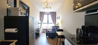 Modern apartment interior with cozy living room and kitchen area, featuring stylish lighting and large window.