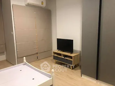 Modern bedroom with minimalist decor, featuring a TV stand and air conditioning.