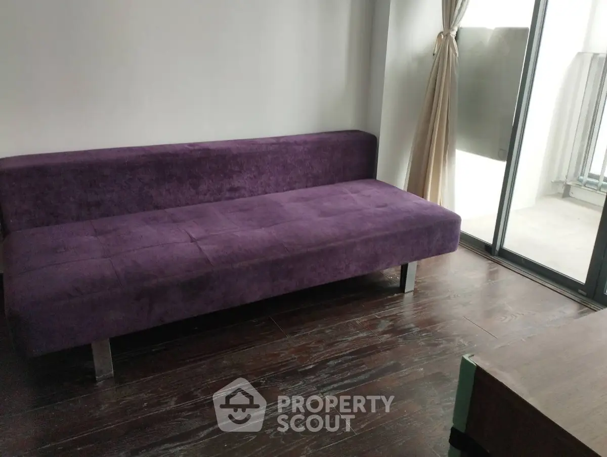 Modern living room with sleek purple sofa and large window for natural light.