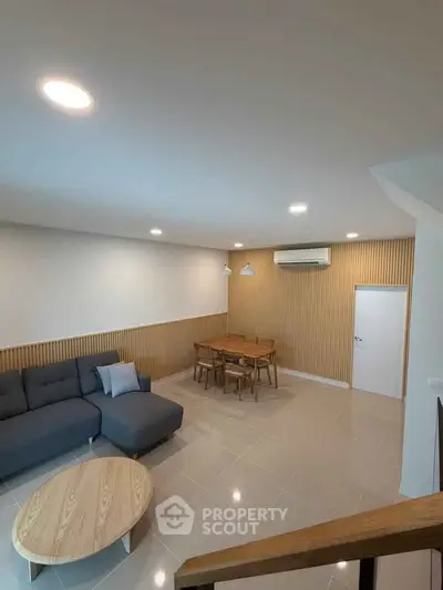 Modern living room with stylish furniture and elegant lighting, featuring a cozy sofa and a chic dining area.