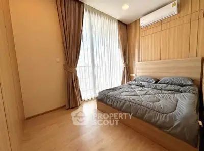 Modern bedroom with wooden flooring and large window for natural light