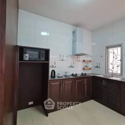 Modern kitchen with dark wood cabinets and gas stove in a bright, tiled space.