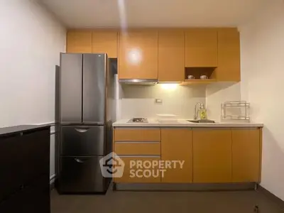 Modern kitchen with sleek cabinetry and stainless steel fridge in cozy apartment.