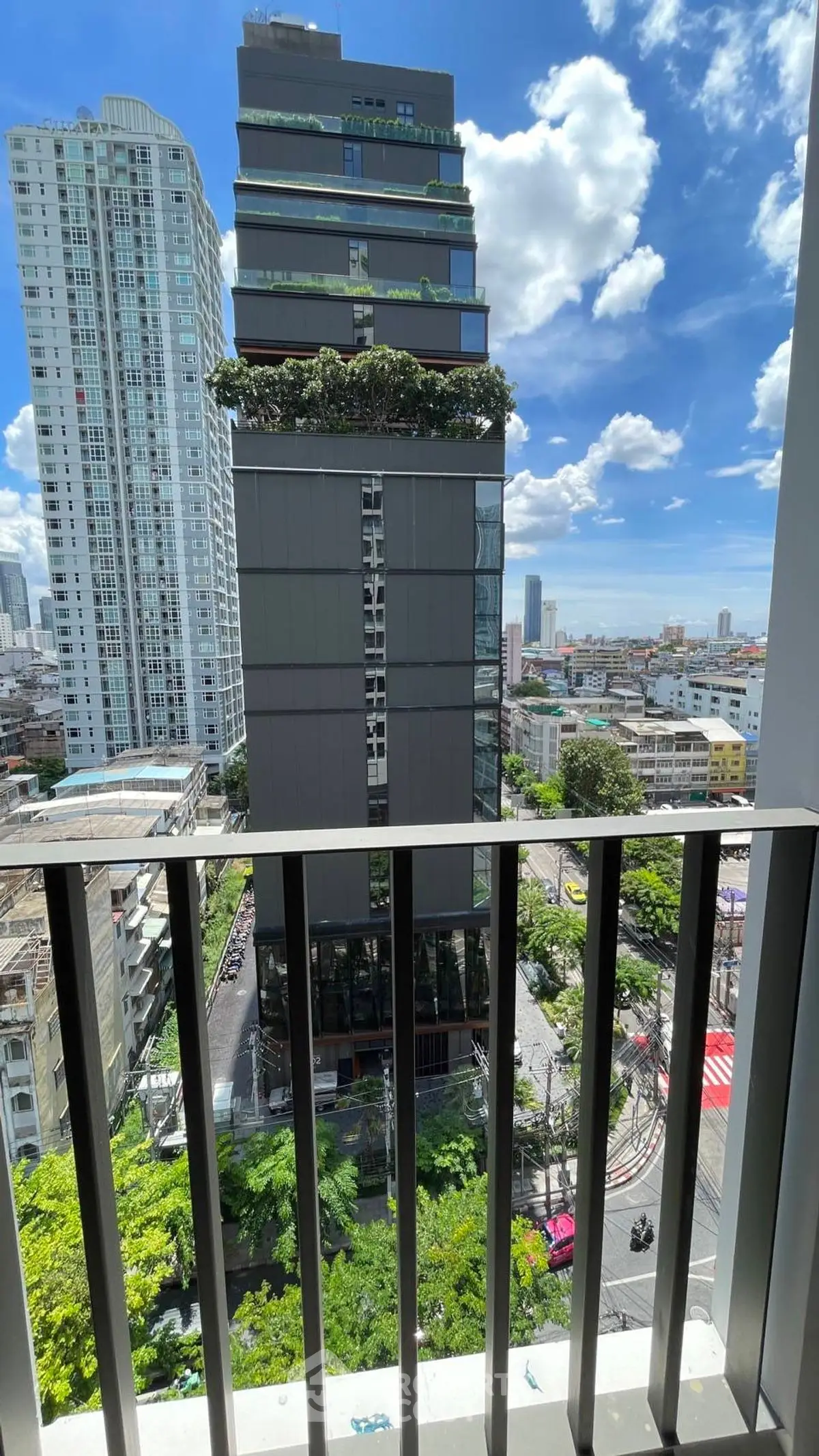 Stunning city view from a modern balcony overlooking urban skyline and lush greenery.
