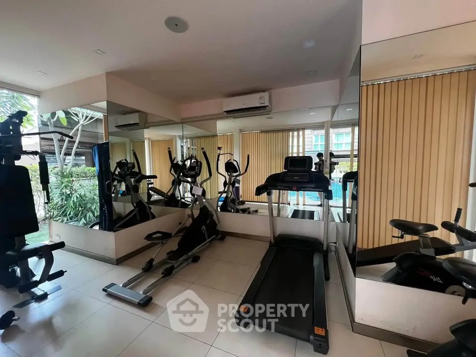 Modern gym with exercise equipment and mirrored walls in a residential building.
