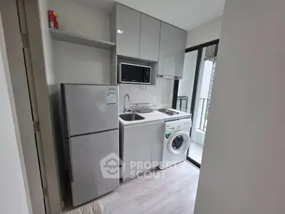 Compact modern kitchen with appliances and balcony access in urban apartment