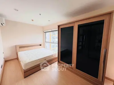 Spacious bedroom with modern wooden wardrobe and large window offering natural light.