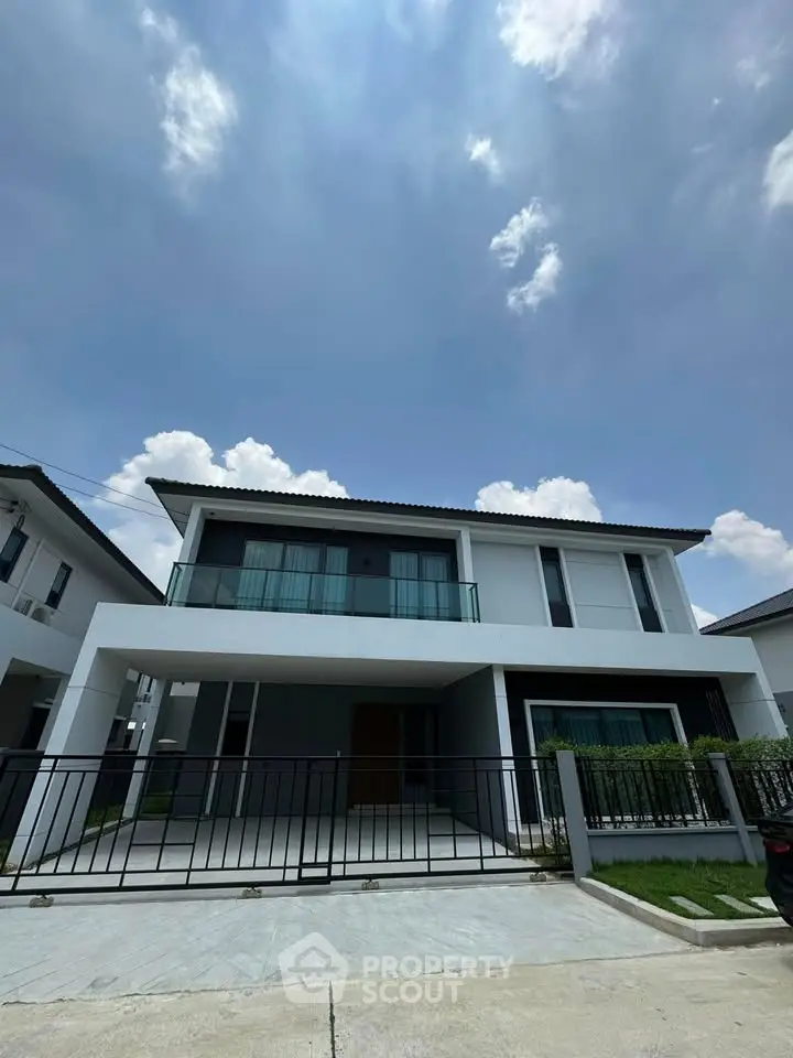 Modern two-story house with sleek design and spacious driveway under a clear blue sky.
