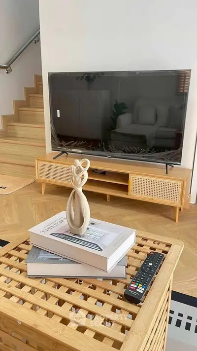 Modern living room with stylish TV stand, decorative books, and remote control on a wooden coffee table.