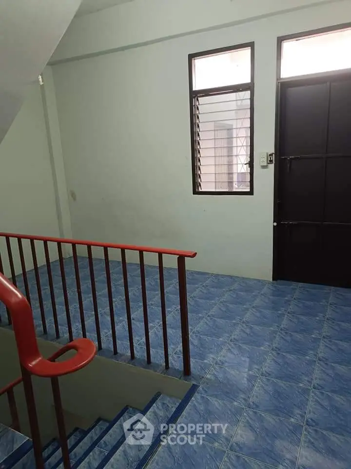 Spacious stairwell with blue tiled flooring and natural light.