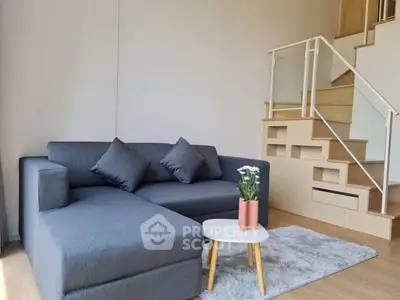 Modern living room with stylish gray sofa and chic staircase design