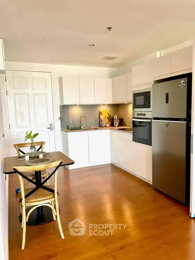 Modern kitchen with sleek appliances and wooden flooring in a cozy apartment.