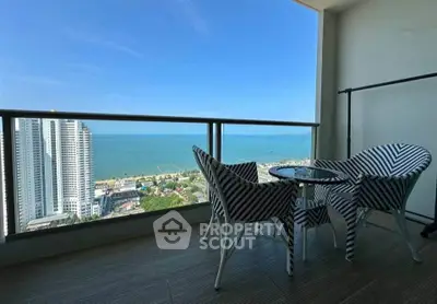 Stunning ocean view from high-rise balcony with stylish seating area.