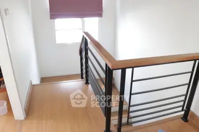 Modern staircase with wooden flooring and sleek metal railing in a bright home interior.