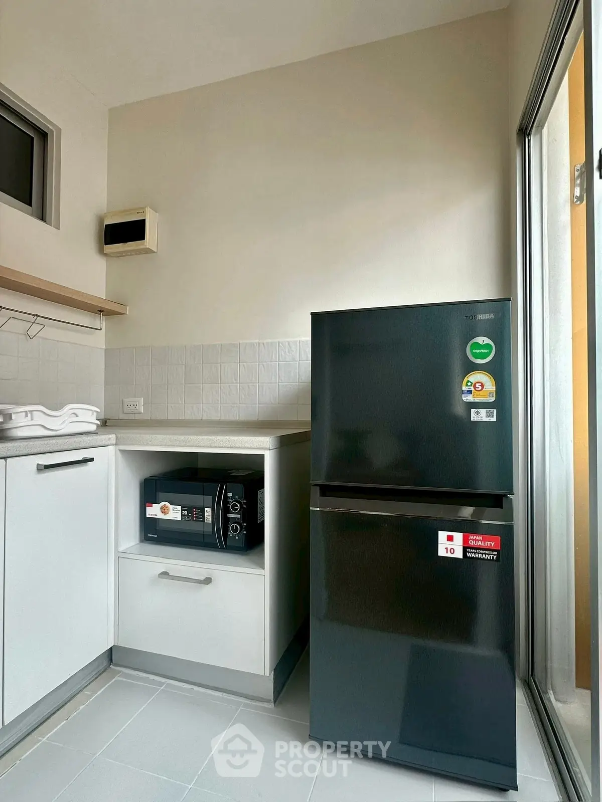 Modern kitchen with sleek black fridge and microwave in compact layout.