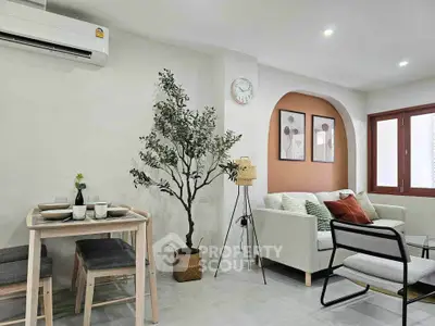 Modern living room with stylish decor, featuring a cozy sofa, dining area, and elegant wall art.
