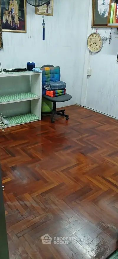 Cozy room with wooden parquet flooring and simple decor, ideal for a home office or study space.