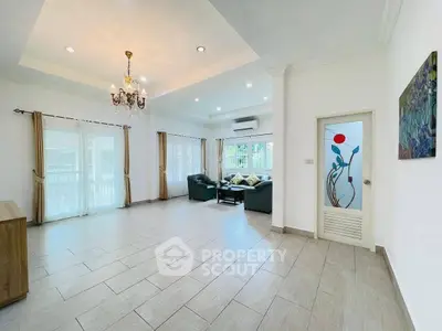 Spacious living room with elegant chandelier and large windows for natural light.