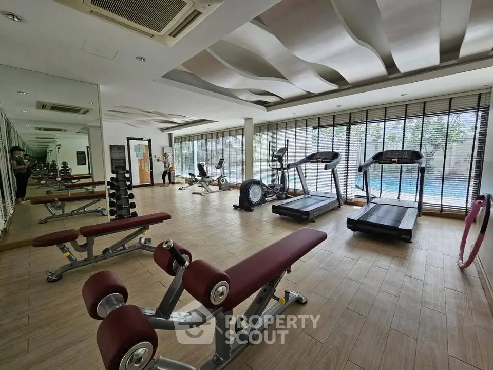 Spacious gym with modern equipment and pool view, perfect for fitness enthusiasts.