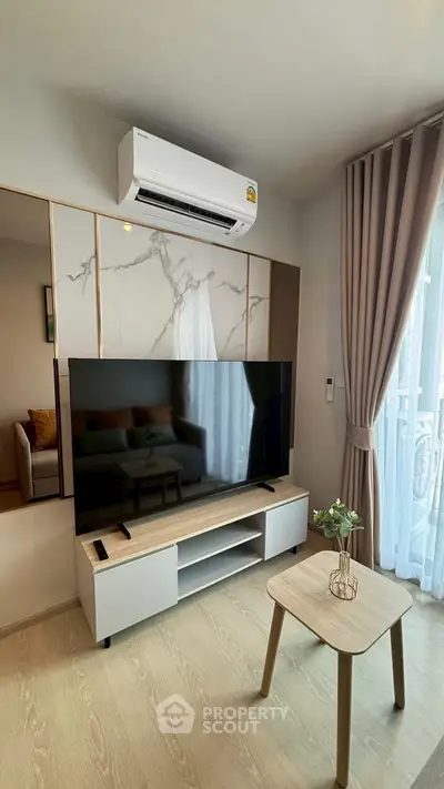Modern living room with air conditioning and large TV, featuring elegant decor and natural light.