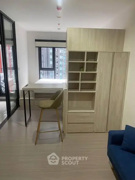 Modern studio apartment with sleek furnishings and large windows for natural light.