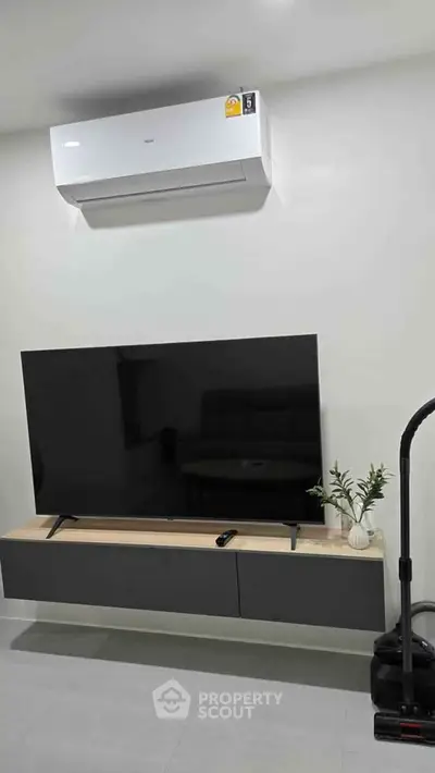 Modern living room with sleek TV setup and air conditioning unit, perfect for comfortable living.