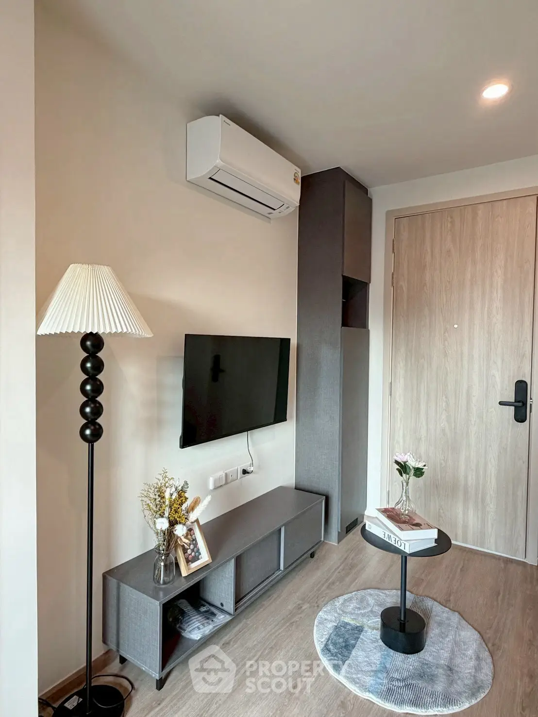 Modern living room with sleek furniture and wall-mounted TV in a cozy apartment.