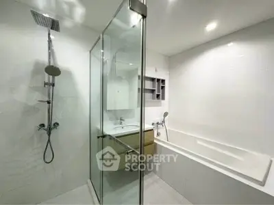 Modern bathroom with glass shower and bathtub in sleek white design.