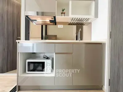 Modern compact kitchen with built-in microwave and sleek cabinetry in a stylish apartment.