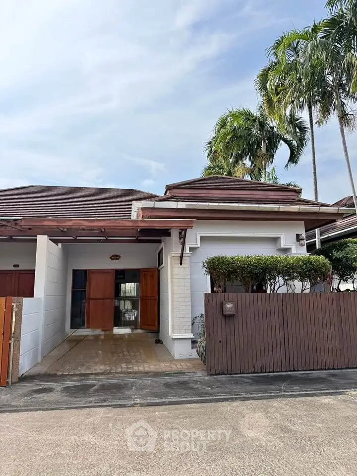 Charming single-story house with lush palm trees and modern wooden accents.