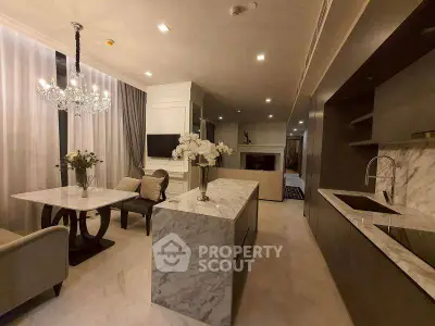 Luxurious open-layout kitchen and dining area with marble countertops and elegant chandelier.