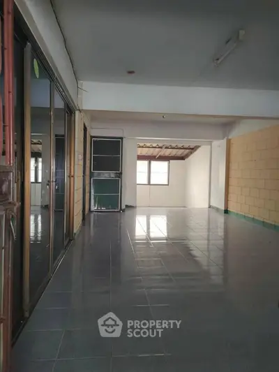 Spacious tiled interior with large windows and sliding glass doors, perfect for versatile living space.