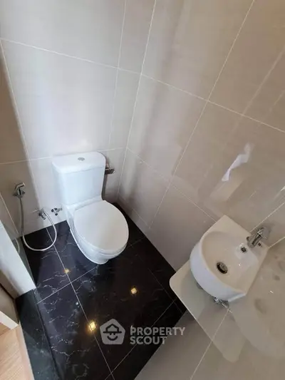 Modern bathroom with sleek black tile flooring and compact fixtures.
