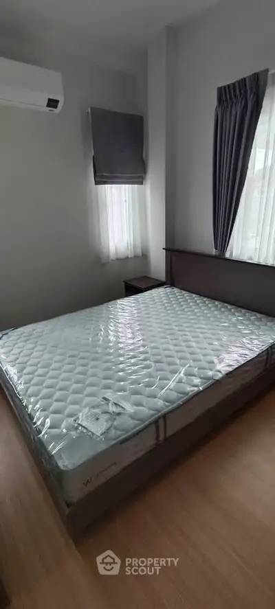 Spacious bedroom with large window and modern air conditioning unit.