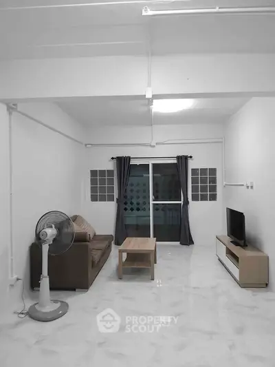 Spacious living room with modern furniture and large window for natural light.