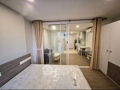 Modern bedroom with sliding glass doors and cozy living area in a stylish apartment.