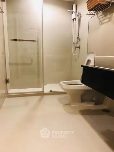 Modern bathroom with glass shower and sleek fixtures in contemporary home.