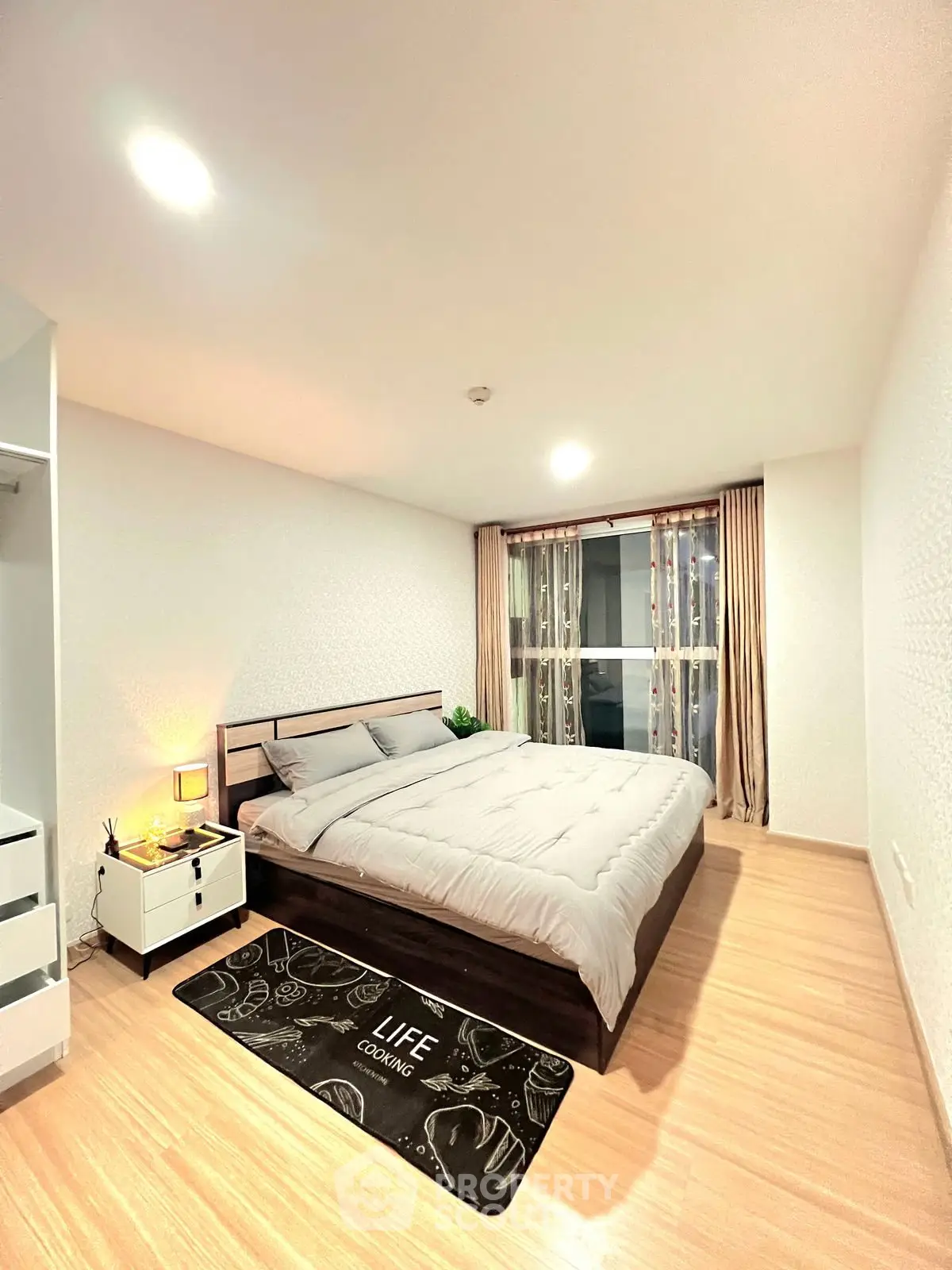 Spacious modern bedroom with cozy decor and large window for natural light.