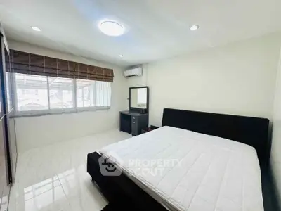 Spacious bedroom with large window and modern furnishings in a bright, airy setting.