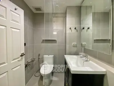 Modern bathroom with sleek fixtures and neutral tiles, featuring a spacious mirror and elegant sink.