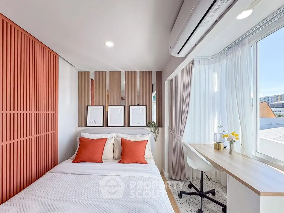 Modern bedroom with stylish decor and large window offering natural light.